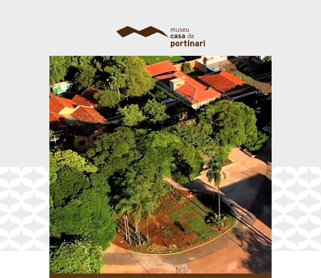 Na parte superior da imagem, o logotipo do Museu Casa de Portinari se destaca sobre um fundo cinza claro. Abaixo, uma fotografia aérea mostra a área externa do museu, cercada por uma grande quantidade de árvores e vegetação, que contrastam com os telhados de telha cerâmica do museu e das casas ao redor. No canto inferior direito, uma praça com caminhos pavimentados, canteiros e palmeiras se integra harmoniosamente ao cenário.